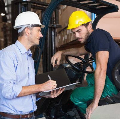 Warehouse manager talking with forklift driver in a large warehouse