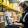 A woman is seen working on a laptop in a warehouse. This image can be used to depict a professional working in a non-traditional office environment.